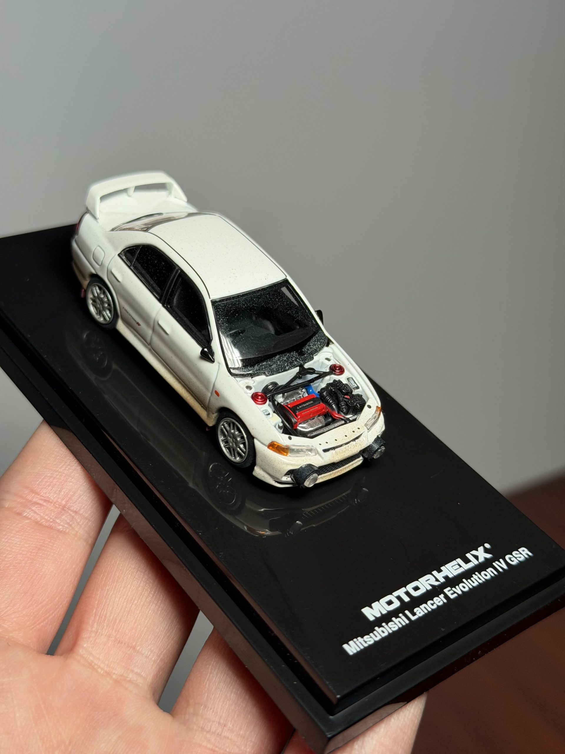MOTORHELIX 1:64 Mitsubishi Lancer Evolution lV Versión embarrada con capó removible